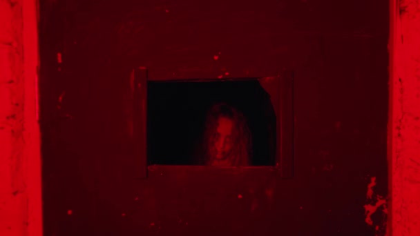 Horror aktorski - kobieta w kaftanie bezpieczeństwa stojąca za drzwiami w szpitalu psychiatrycznym - coraz bliżej i patrząc rzuca małe okno — Wideo stockowe