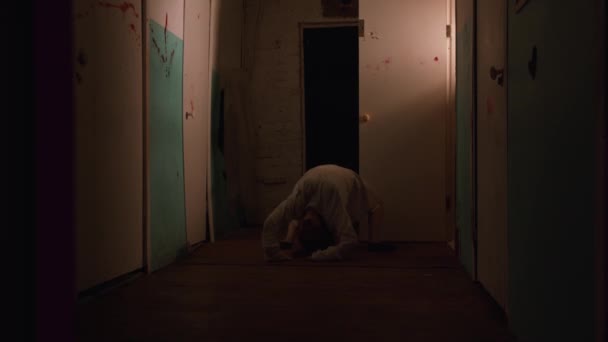 Horror aktorski - kobieta w kaftanie bezpieczeństwa szaleje w zakrwawionym korytarzu szpitala psychiatrycznego — Wideo stockowe