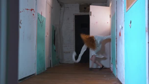 Horror aktorski - kobieta w kaftanie bezpieczeństwa uciekła z pokoju w szpitalu psychiatrycznym i szła do kamery — Wideo stockowe