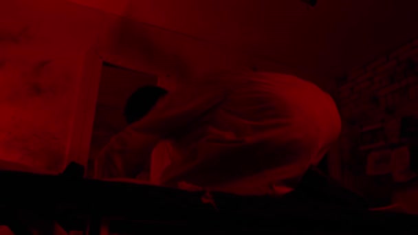 Šílenec ve svěrací kazajce se zblázní, sedí na posteli v cele psychiatrické léčebny a útočí na kameramana — Stock video