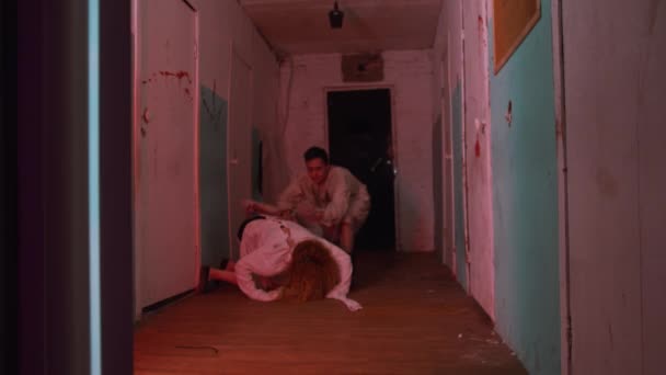 Actuación de terror - hombre y mujer enloqueciendo y arrastrándose por el pasillo de un hospital mental sangriento aterrador — Vídeos de Stock