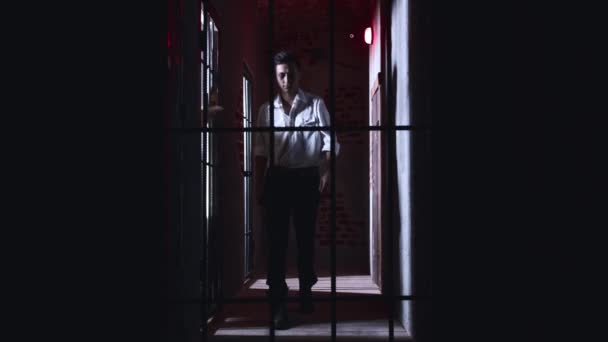 Skräckskådespeleri - en fängelsedirektör går runt cellerna i fängelset och fångar honom och stryper honom med handen — Stockvideo