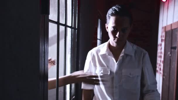 Hrůza - dozorce chodí po celách ve vězení a vězeň ho chytí a uškrtí jeho rukou přes mříže — Stock video