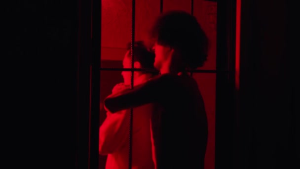 Skräckskådespeleri - en manlig fånge stryper fängelsedirektören med handen genom cellstolarna i rött ljus — Stockvideo