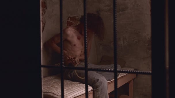 Actuación de terror - un hombre sin camisa luchando en la celda de la prisión queriendo suicidarse - sosteniendo un lazo de cuerda — Vídeos de Stock