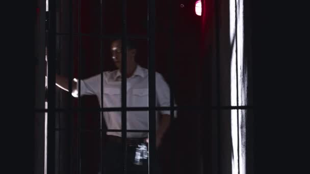 Skräckskådespeleri - en fängelsedirektör går runt i cellerna i fängelset och släpper ut en fånge från cellen och tänker döda honom med en pistol — Stockvideo