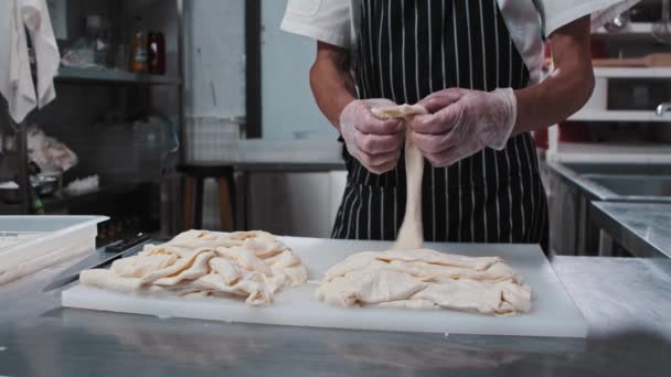 Pieces of stretching cheese on a board and a man stretches it into slices — Stock Video