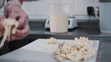Kesilmiş yumuşak peyniri bir fıçının içine koyan bir adam.