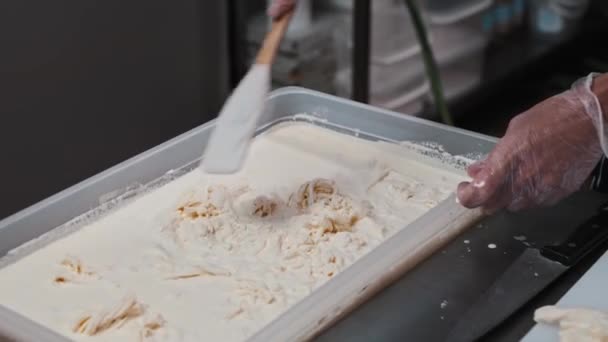 Мужчина смешивает сыр моцарелла с лопаткой в чане с жидкостью — стоковое видео