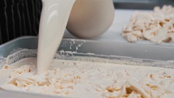 Un hombre vertiendo un líquido en una tina llena de queso blando — Vídeos de Stock