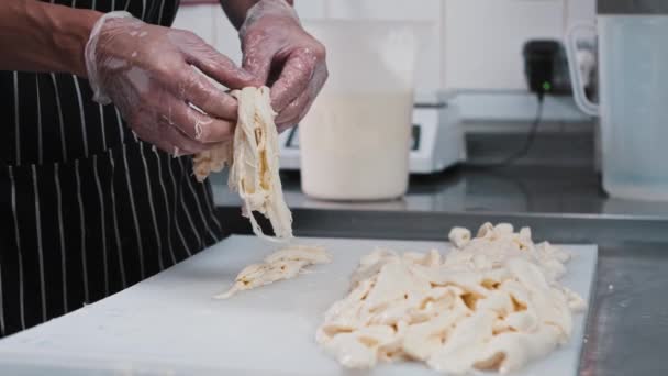 A man worker rips soft cheese into pieces — Stock Video