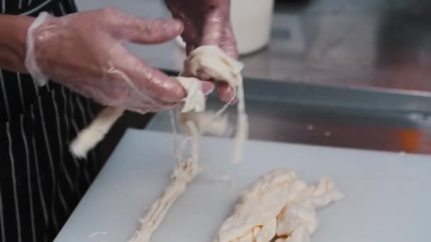 A man worker rips soft cheese into long pieces — Stock Video