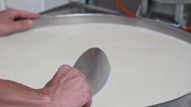 Peynir fabrikası - bir fıçıyla çalışan adam yumuşak peynirin temeli - tabanı demir bir plaka ile kontrol ediyor