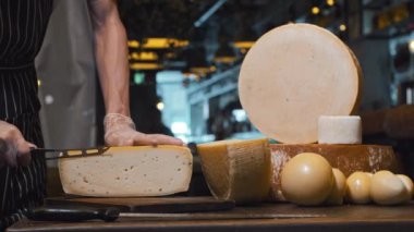 Peynir dükkanında bir adam koca bir peynir kafasının küçük bir parçasını kesiyor.