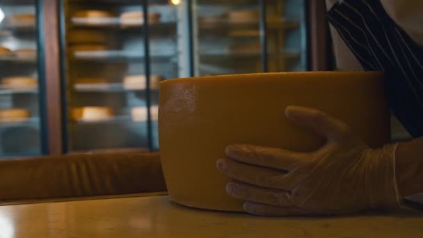 Un uomo mette una grande testa di formaggio sul tavolo e lo trasferisce in frigo. — Video Stock