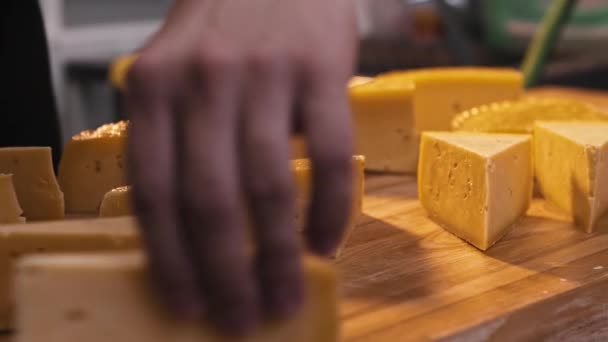 Un hombre en una tienda de quesos corta una enorme cabeza de queso con un cuchillo en trozos triangulares — Vídeos de Stock