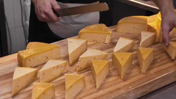 Un homme dans la boutique coupe une tête de fromage avec un couteau en morceaux triangulaires — Video