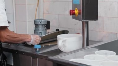 Peynir fabrikası. Eldivenli adam peynir yapma makinesiyle çalışıyor.
