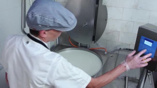 La fábrica del queso - el hombre se acerca a la tina del queso suave y comprueba la preparación — Vídeos de Stock