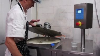 Peynir üretim fabrikasında çalışan bir adam. Peynir bazlı bir fıçı açıyor.