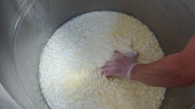 Bir işçi fabrikadaki bir fıçıdan yumuşak peynirle sıvıyı topluyor.