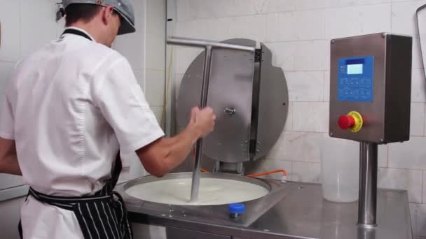 Un hombre que trabaja en la fábrica de producción de queso, añadiendo un espesante en una cuba con una base de queso — Vídeos de Stock