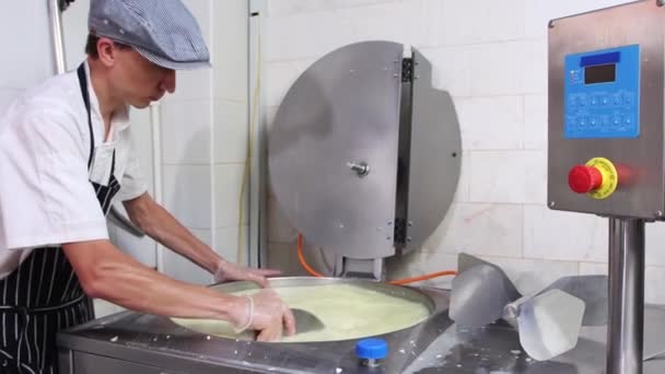 Un hombre que trabaja en una fábrica de quesos - mezclando pequeños trozos de queso blando en una cuba — Vídeos de Stock