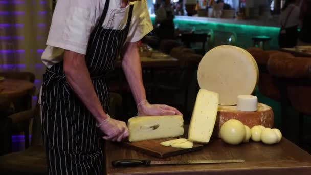 Restoran servisi. Adam peynir kafanın küçük bir parçasını bıçakla kesiyor ve kameraya bakıyor. — Stok video