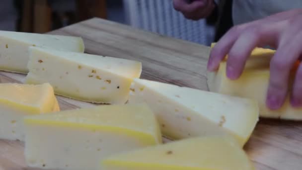 Ресторан обслуживающий - человек отрезает треугольные куски сыра с ножом на столе — стоковое видео