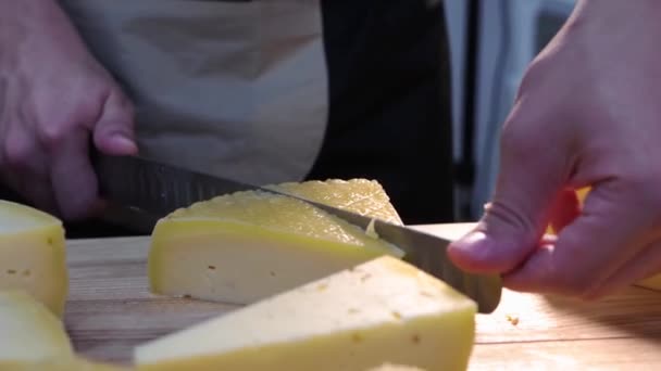 Ресторан обслуживающий - человек работник отрезает треугольные куски сыра с ножом на столе — стоковое видео