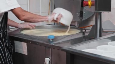 Peynir fabrikası - eldivenli adam peynir yapma makinesiyle çalışıyor - fıçıdan fazla su çıkarıyor.