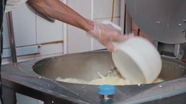 Peynir yapan fabrika - eldivenli adam peynir yapma makinesiyle çalışıyor - fıçıdan fazla su çıkarıyor.