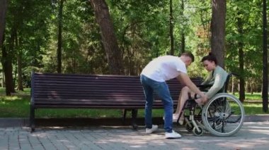 Engelli bir kadının tekerlekli sandalyeden kürsüye oturmasına yardım eden bir adam.