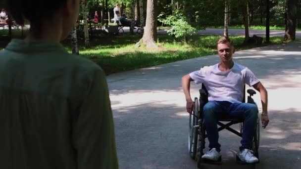 Un homme en fauteuil roulant marchant dans le parc et y rencontrant son amie - embrasser — Video