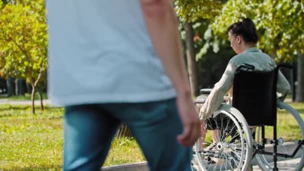 Dois caras ajudando uma mulher em uma cadeira de rodas para superar o passeio — Vídeo de Stock
