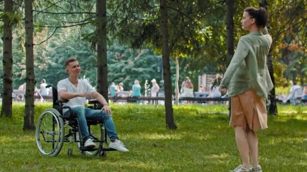 Чоловік у інвалідному візку та його подруга грають в парку — стокове відео