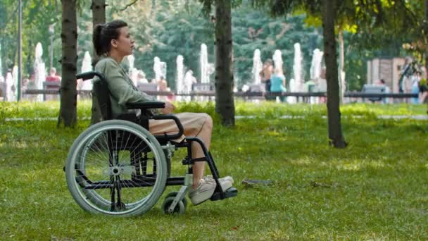 Solo triste donna su una sedia a rotelle seduta nel parco — Video Stock