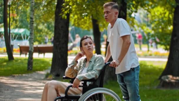 Vrienden in het park - een man die praat met een gehandicapte vrouw in een rolstoel — Stockvideo