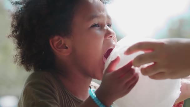 Czarna dziewczynka jedząca watę cukrową z rąk matki — Wideo stockowe