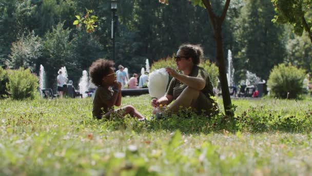 Μικτή οικογένεια της μητέρας και της κόρης σε γυαλιά ηλίου ξοδεύουν χρόνο στο πάρκο - τρώει μαλλί της γριάς — Αρχείο Βίντεο