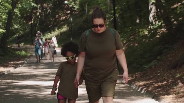 Vit kvinna och hennes svarta dotter på promenad - håller hand — Stockvideo