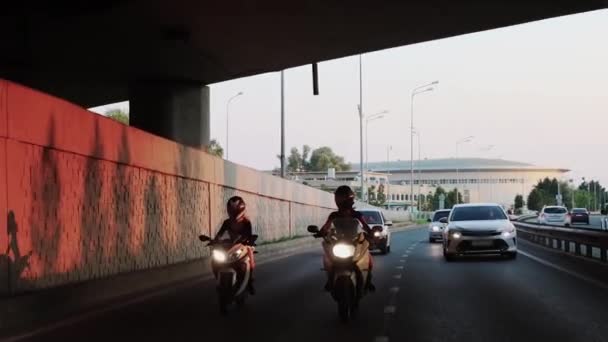 Dvě mladé ženy na motorce na silnici pod mostem — Stock video