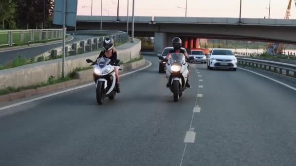 Zwei junge Frauen mit Motorrädern am frühen Abend auf einer Straße — Stockvideo