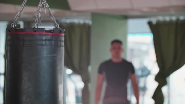 Un hombre se dirige a un saco de boxeo en el pasillo — Vídeo de stock