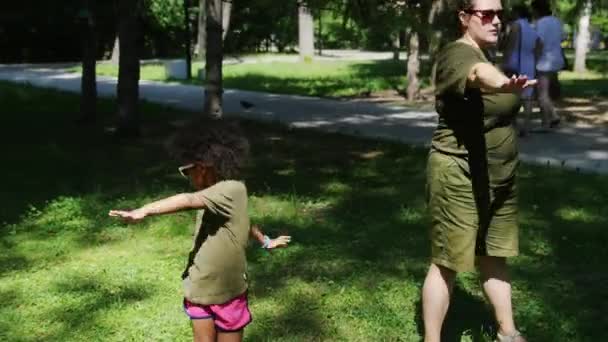 Famille mixte - femme blanche et sa fille noire faisant de simples exercices d'échauffement dans le parc vert — Video