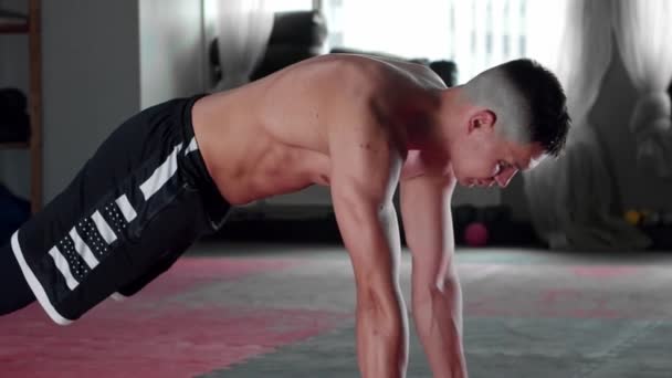Młody mężczyzna bez koszulki robi pompki na siłowni — Wideo stockowe