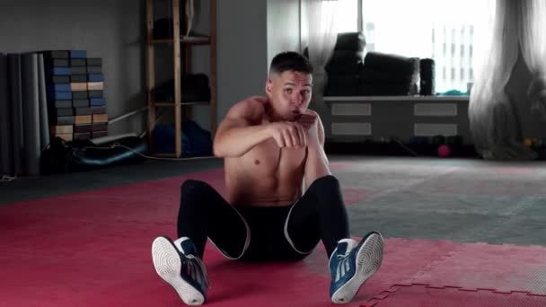 Joven bombeando sus abdominales y boxeando en el gimnasio mirando a la cámara — Vídeos de Stock