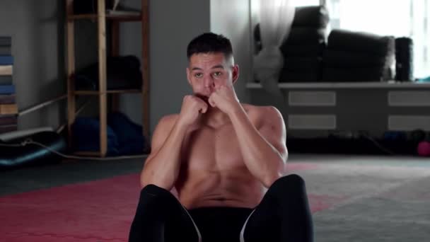 Ung man med kort hår pumpande hans abs och boxning i gymmet - tittar i kameran — Stockvideo
