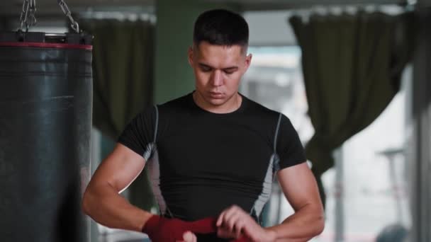 Joven boxeador ata su mano con vendajes rojos — Vídeos de Stock