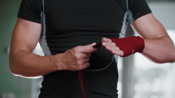 Młody bokser wiąże dłoń czerwonymi bandażami — Wideo stockowe